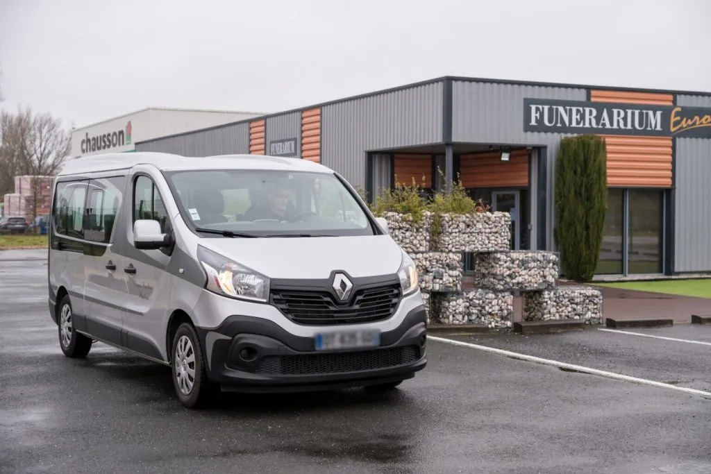 Véhicule de transport funéraire Renault gris stationné devant le bâtiment d'un funérarium