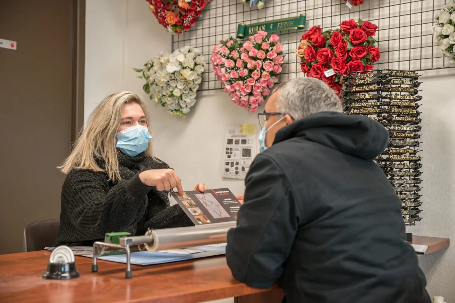 Conseillère funéraire portant un masque expliquant une brochure d'obsèques à un client
