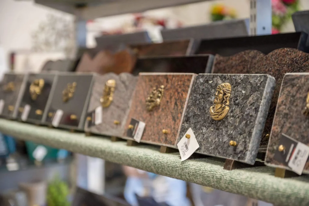 Gros plan sur une étagère exposant diverses plaques funéraires gravées.