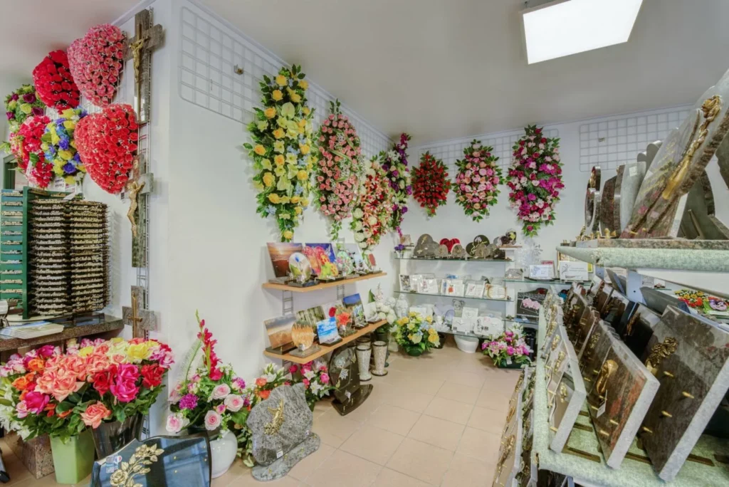 Salle d'exposition présentant des plaques en granit, compositions florales et croix pour obsèques