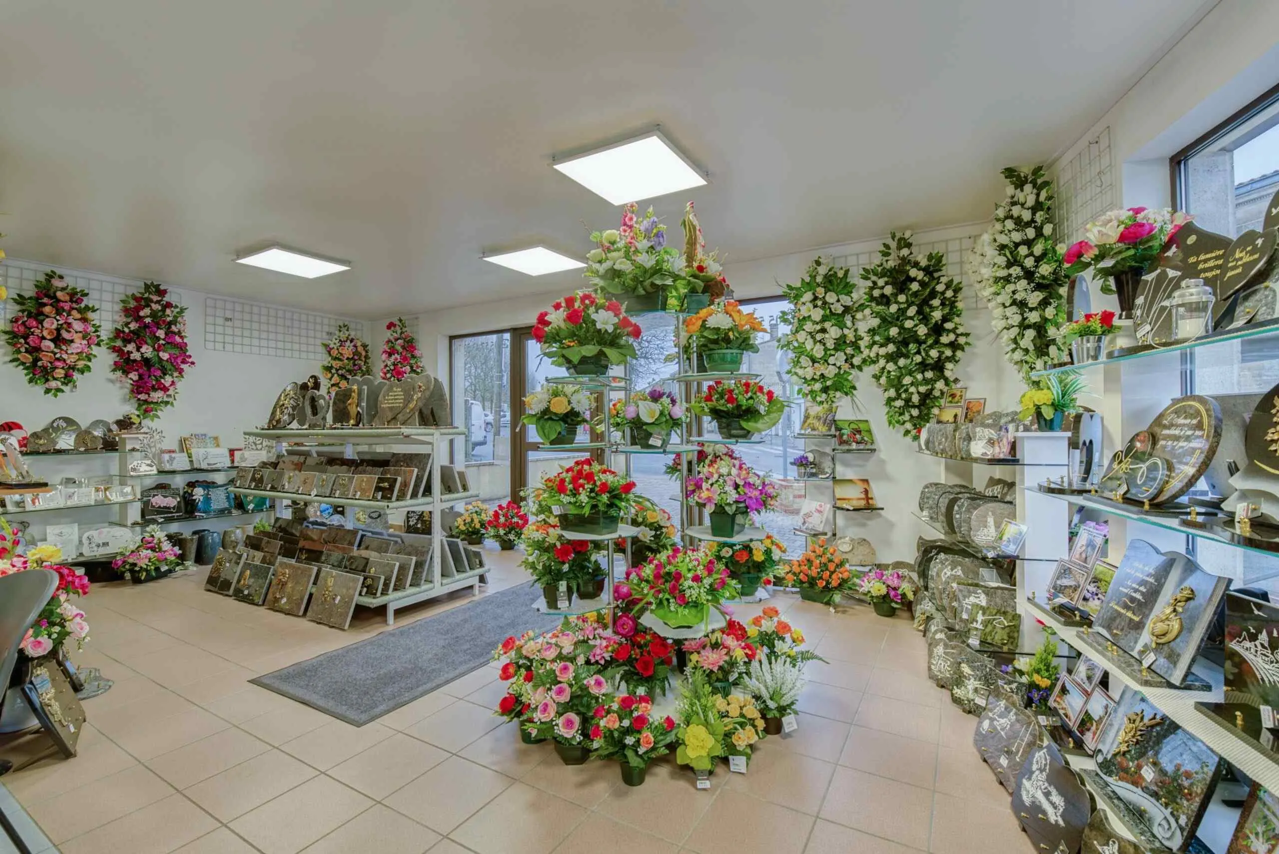 Vue d'un magasin d'articles funéraires proposant des fleurs de deuil et des plaques en granit