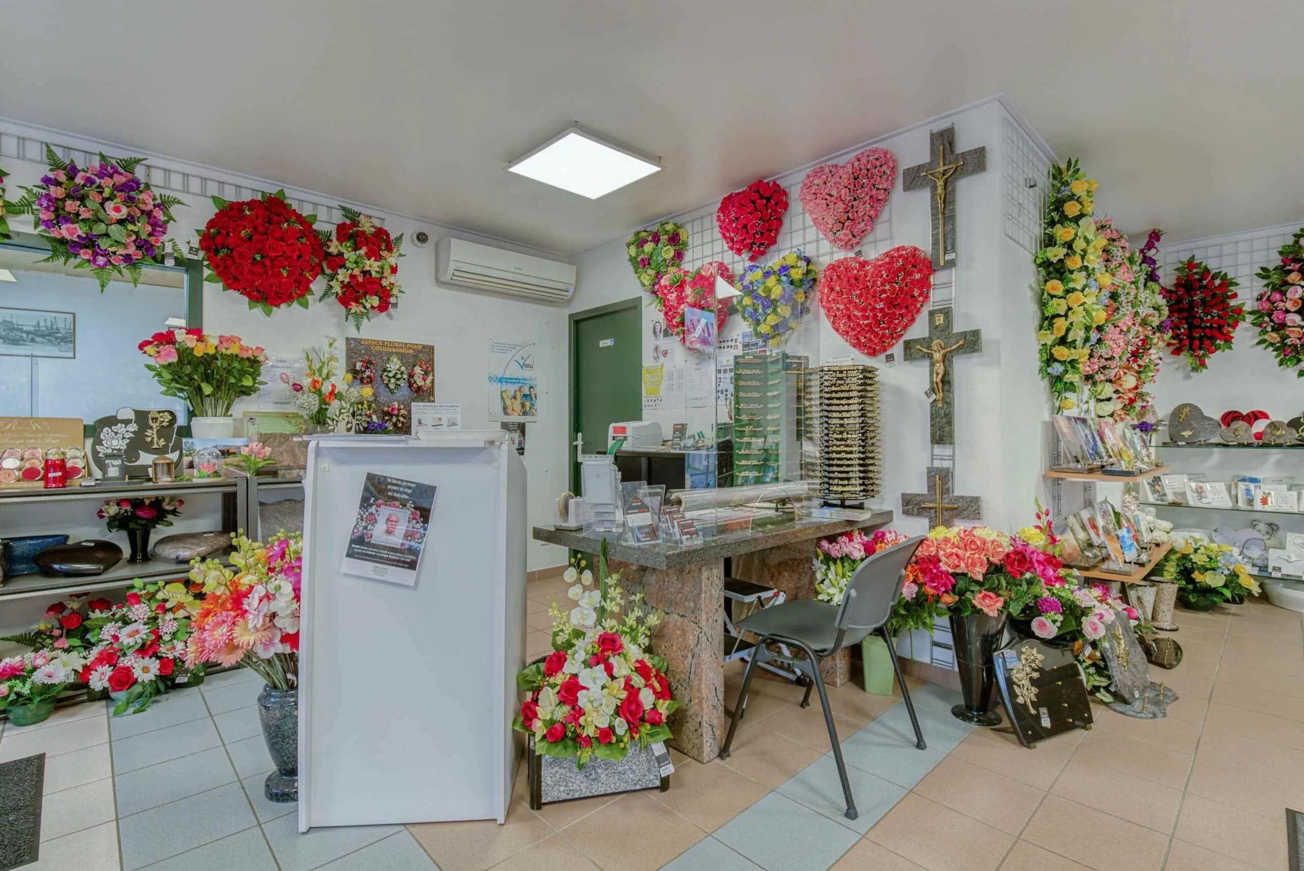 Comptoir d'accueil de pompes funèbres décoré de couronnes en forme de cœur et fleurs de deuil